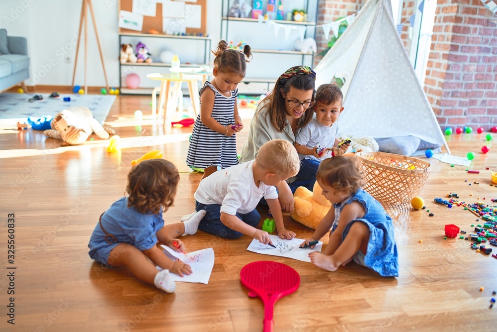 Wall mural beautiful teacher and group of toddlers sitting on the floor drawing using paper and pencil around l