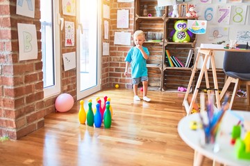 Young caucasian kid playing at kindergarten with toys. Preschooler boy happy at playroom.