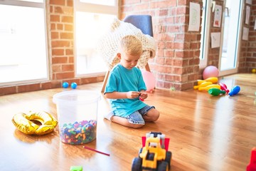 Young caucasian kid playing at kindergarten with toys. Preschooler boy happy at playroom.