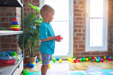 Young caucasian kid playing at kindergarten with toys. Preschooler boy happy at playroom.