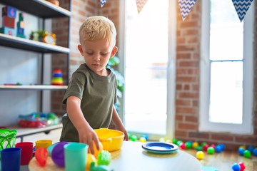 Young caucasian kid playing at kindergarten with toys. Preschooler boy happy at playroom.
