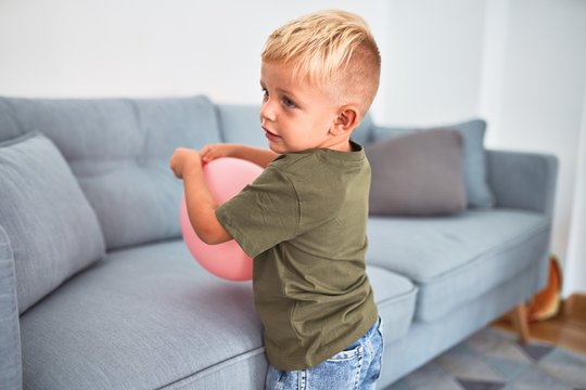 Young caucasian kid playing at kindergarten with toys. Preschooler boy happy at playroom.