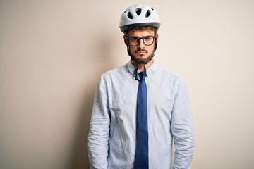 Young businessman wearing glasses and bike helmet standing over isolated white bakground skeptic and nervous, frowning upset because of problem. Negative person.