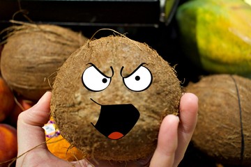 Hand holding coconut with cartoon eyes and mouth 