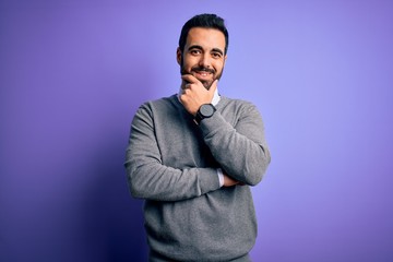 Obraz premium Handsome businessman with beard wearing casual tie standing over purple background looking confident at the camera smiling with crossed arms and hand raised on chin. Thinking positive.