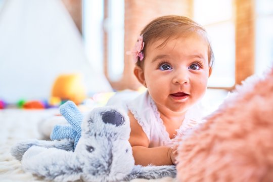 Beautiful infant happy at kindergarten around colorful toys lying on blacket