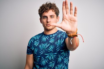 Young blond handsome man on vacation with curly hair wearing casual summer t-shirt doing stop sing...