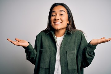 Young beautiful asian woman wearing casual shirt standing over isolated white background clueless...