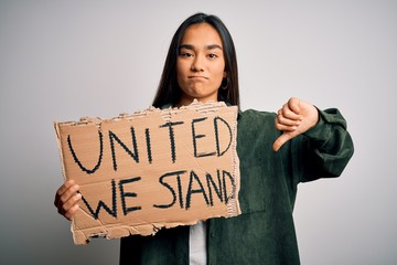Young beautiful activist asian woman asking unity holding banner with united stand message with...