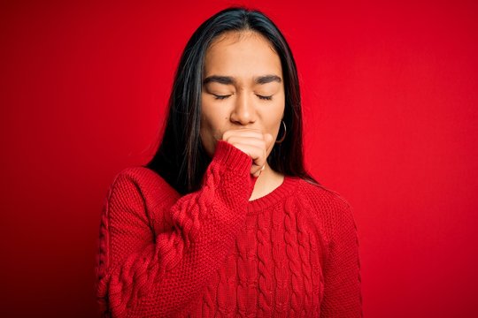 Young beautiful asian woman wearing casual sweater standing over isolated red background feeling unwell and coughing as symptom for cold or bronchitis. Health care concept.