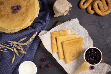 Stack of pancakes for Maslenitsa with honey and jam, top view on a wooden Board in the Russian style