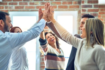 Group of business workers standing with hands together highing five at the office