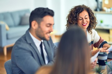 Group of business workers smiling happy working together. Sitting on desk speaking with smile on face at the office