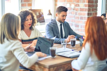 Group of business workers working together. Sitting on desk using laptop reading documents at the office