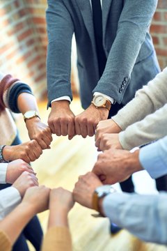 Group of business workers standing bumping fists at the office