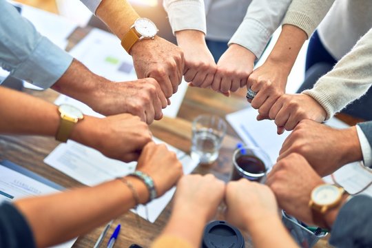 Group of business workers standing bumping fists at the office