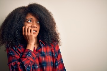 Young beautiful african american woman wearing casual shirt over isolated background looking stressed and nervous with hands on mouth biting nails. Anxiety problem.