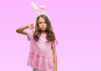 Brunette hispanic girl wearing easter rabbit ears with angry face, negative sign showing dislike with thumbs down, rejection concept