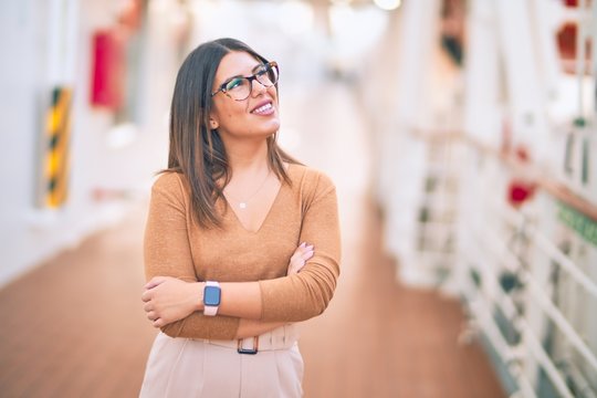 Young beautiful woman on vacation smiling happy and confident. Standing on a deck of ship with smile on face doing a cruise