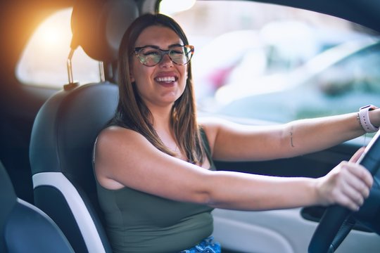 Young beautiful woman smiling happy  and confident. Sitting with smile on face driving a car