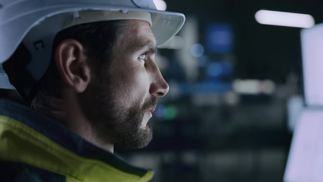 Industry 4.0 Modern Factory: Portrait of Facility Operator Controls Workshop Production Line, Uses Computer with Screens Showing Complex UI of Machine Operation Processes, Controllers