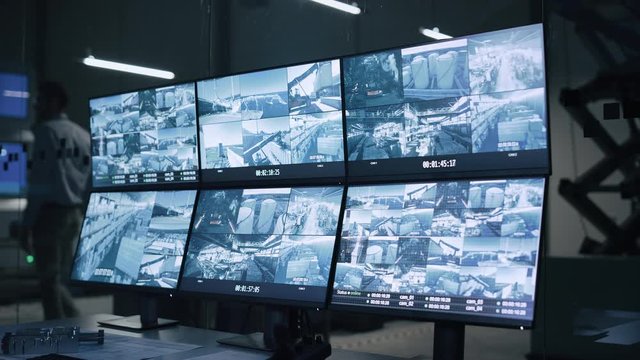 Industry 4.0 Modern Factory: Security Control Room with Multipoke Computer Screens Showing Surveillance Camera Footage Feed. High-Tech Security