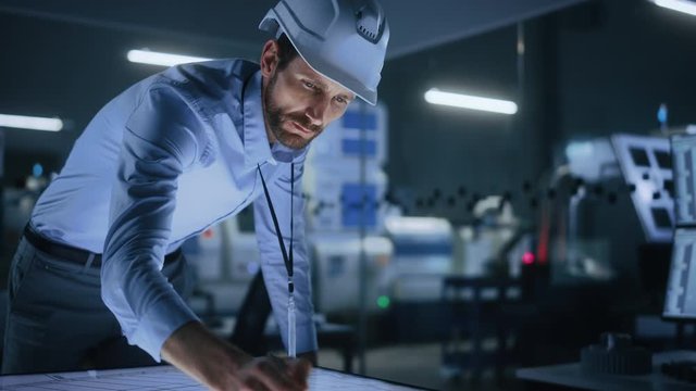 Industry 4.0 Modern Factory Office Meeting Room: Handsome Male Engineer Wearing Hardhat, Uses Pen on Touchscreen Digital Table to Correct, Draw Machinery Blueprints. High-Tech Electronics Facility 