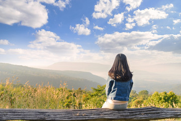 Young traveller woman sitting on wood bench, relaxing and enjoying the panoramic view of on the morning