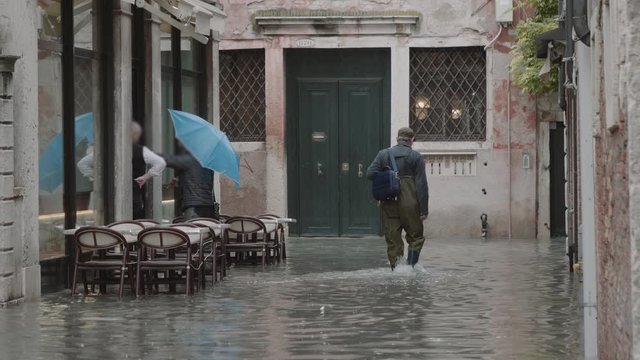 Man working on the outside restaurant tables during the flood  (acqua alta) in Venice, Italy. Venice high water. 4k