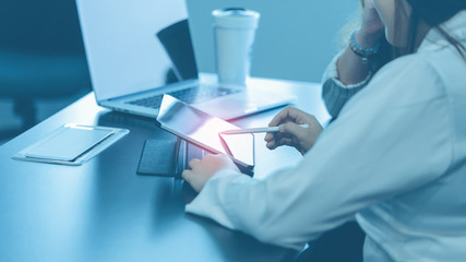 Two young business women sitting at table. First woman holding stylus pen and point to digital...