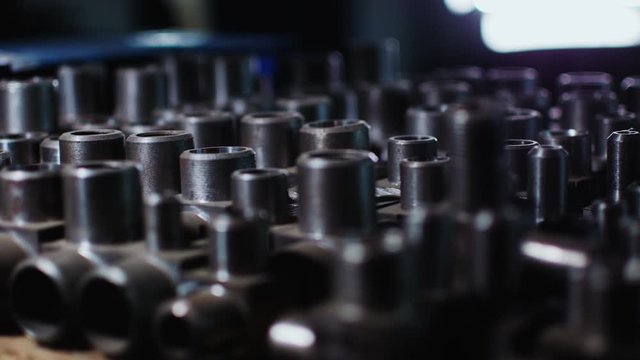 numerous shiny metal pipe joints on table in dark background