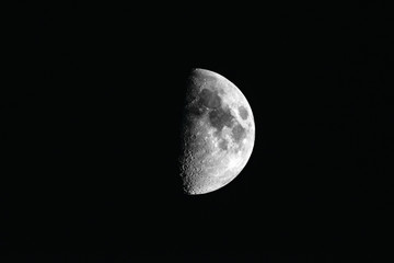 Half moon with visible craters and rivers with dark side of the moon
