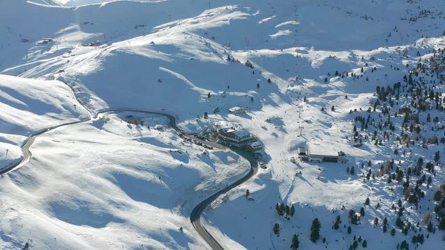 Bird's eye view of the Passo Gardena, in the Dolomites, South Tyrol in Italy. The road is meandering between the snow-covered hills. Many skiers are on the slopes, riding Sella Ronda ski circuit