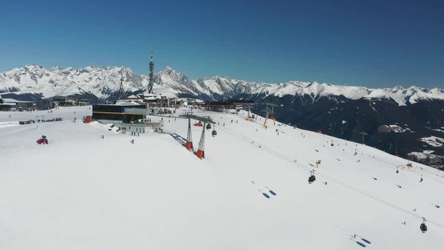 Aerial view of the Kronplatz mountain, Italy. Ski lifts carry skiers up the mountain. People flood the slopes enjoying a beautiful sunny winter day, fresh snow and clear blue sky in the Dolomites.