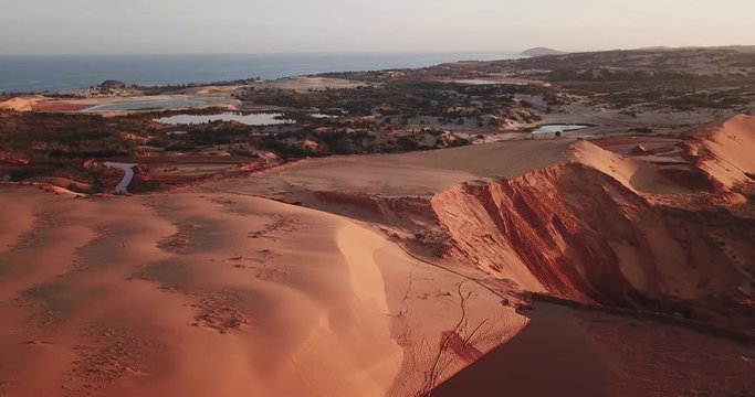 Red sand dunes getting destroyed by a sand mining operation with basins visible in the background and erosion on the side