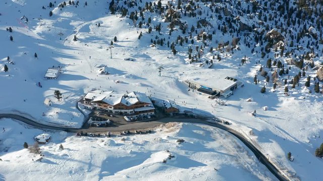 Aerial view of the Passo Gardena, in the Dolomites of the South Tyrol in Italy. The road is meandering between the snow-covered hills. Many skiers are on the slopes, enjoying Sella Ronda circuit.