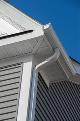 Colonial white gutter guard system,  soffit providing ventilation to the attic, with gray vinyl horizontal siding at a luxury American single family home neighborhood USA © tamas