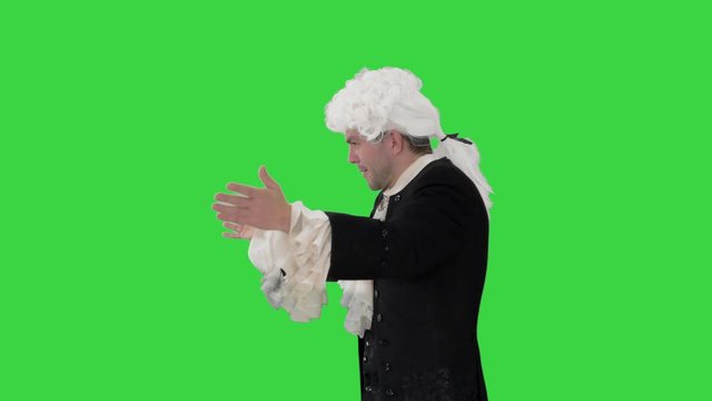 Man dressed like Wolfgang Amadeus Mozart conducting an orchestra on a Green Screen, Chroma Key.