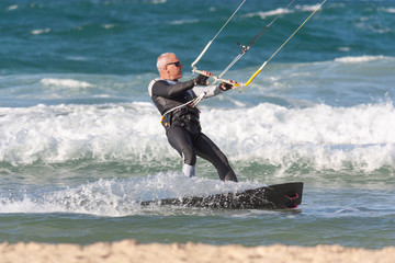 A man over 60 years old rides a kiteboarding