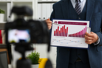 Male in suit and tie show stats graph pad making promo videoblog or photo session in office camcorder to tripod closeup. Vlogger selfie sale solution or finance advisor management information © H_Ko