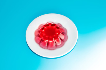 top view of red berry jelly in a white plate on a blue background