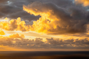 Fototapeta premium Aerial view of beautiful clouds lit by evening sunlight over dark ocean waters