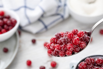 Fresh ripe cranberries with sugar in a spoon. Organic food containing vitamin C. Selective focus.