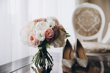 a bouquet of pink flowers, white flowers and greenery is on the table, next to are women's shoes