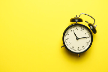 twin bell alarm clock on yellow background. copy space. flat lay