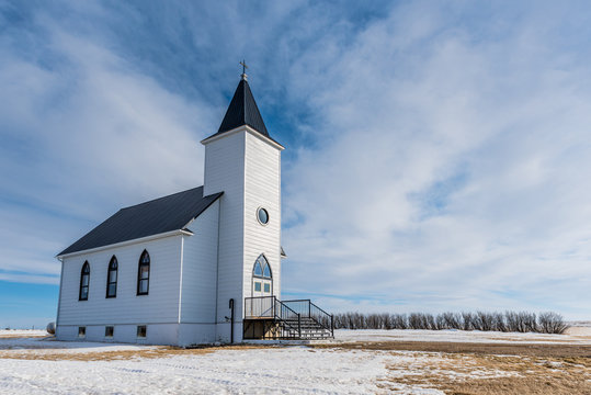 Blue sky and snow surround the historic yet abandoned Trinity Lutheran Church in the ghost town of St. Boswells, SK