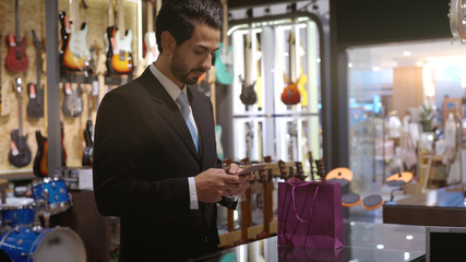 An upwardly mobile Middle Eastern man using a mobile phone - smartwatch to purchase product at the point of sale terminal in a retail store with nfc identification payment for verification