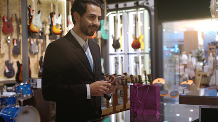 An upwardly mobile Middle Eastern man using a mobile phone - smartwatch to purchase product at the point of sale terminal in a retail store with nfc identification payment for verification