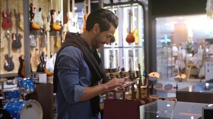An upwardly mobile Middle Eastern man using a mobile phone - smartwatch to purchase product at the point of sale terminal in a retail store with nfc identification payment for verification