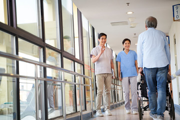 asian employee greeting residents in hallway of nursing home © imtmphoto